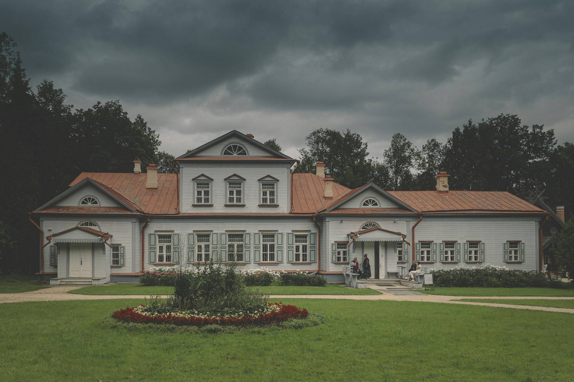 Biały dwór z portykiem wśród drzew